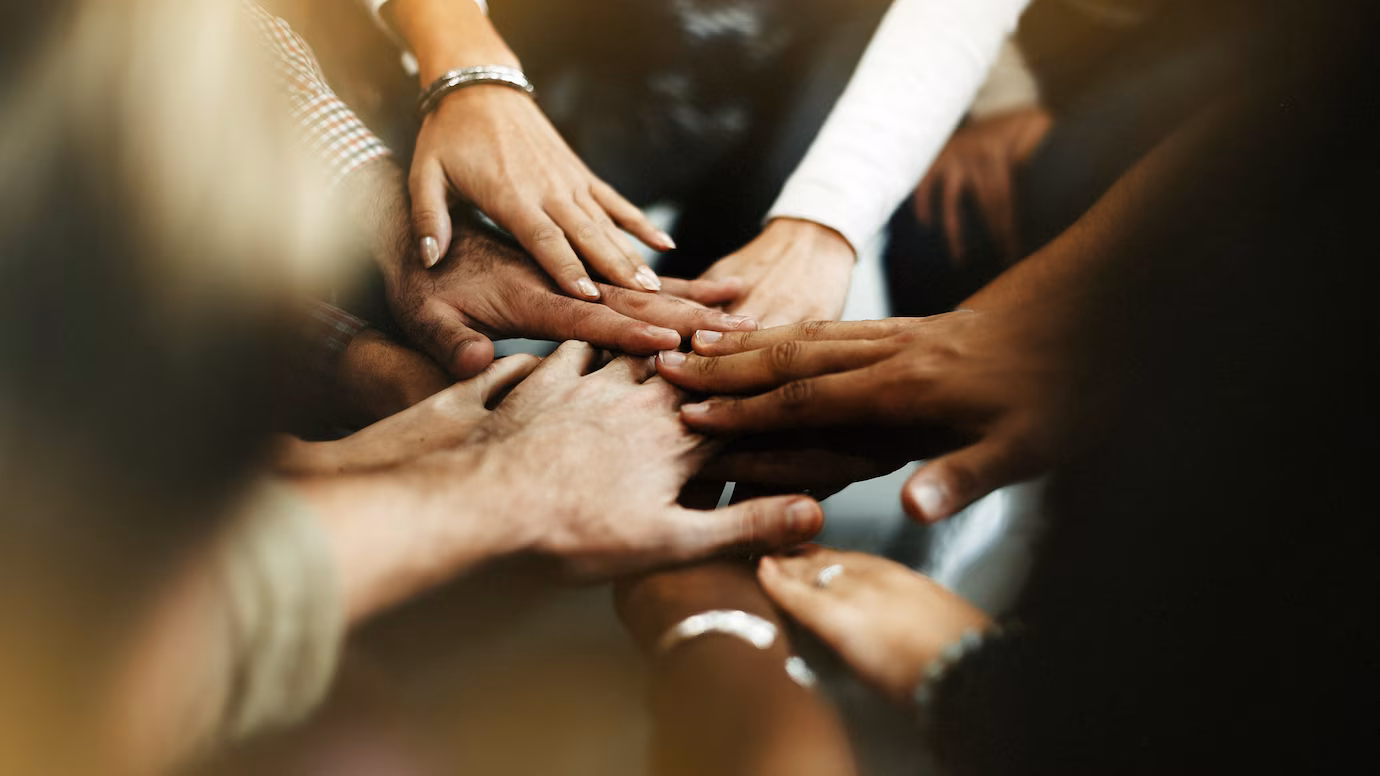Grupo de pessoas dando as mãos em união