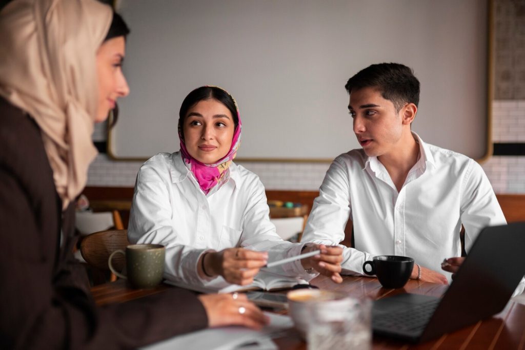 Homem e duas mulheres conversando e tomando café em uma mesa
