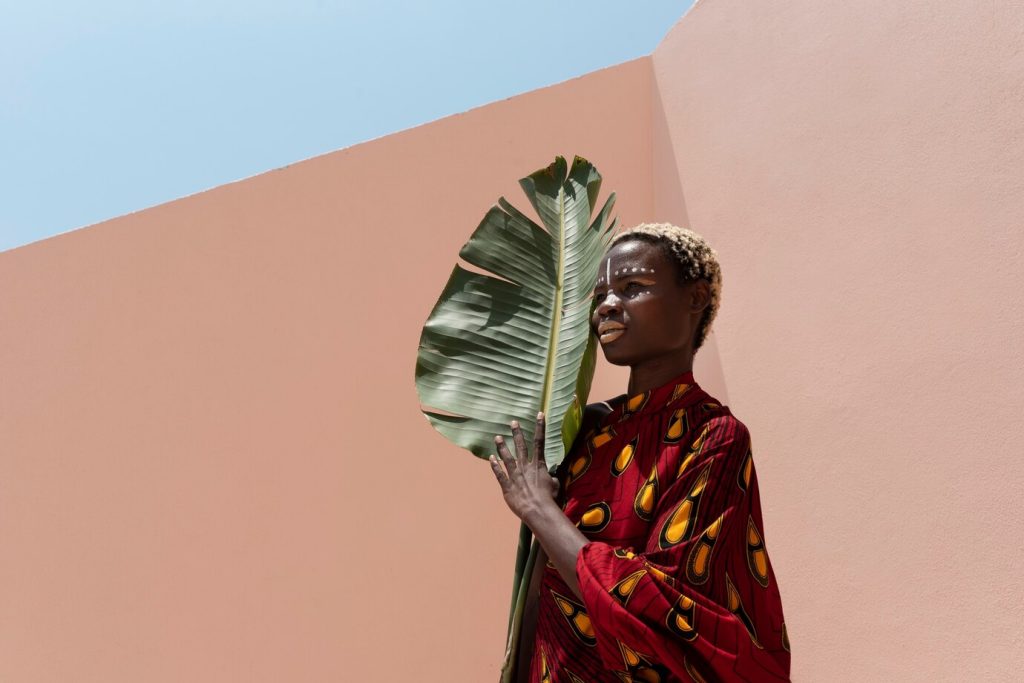 Mulher com roupa de estampas africanas segurando folha