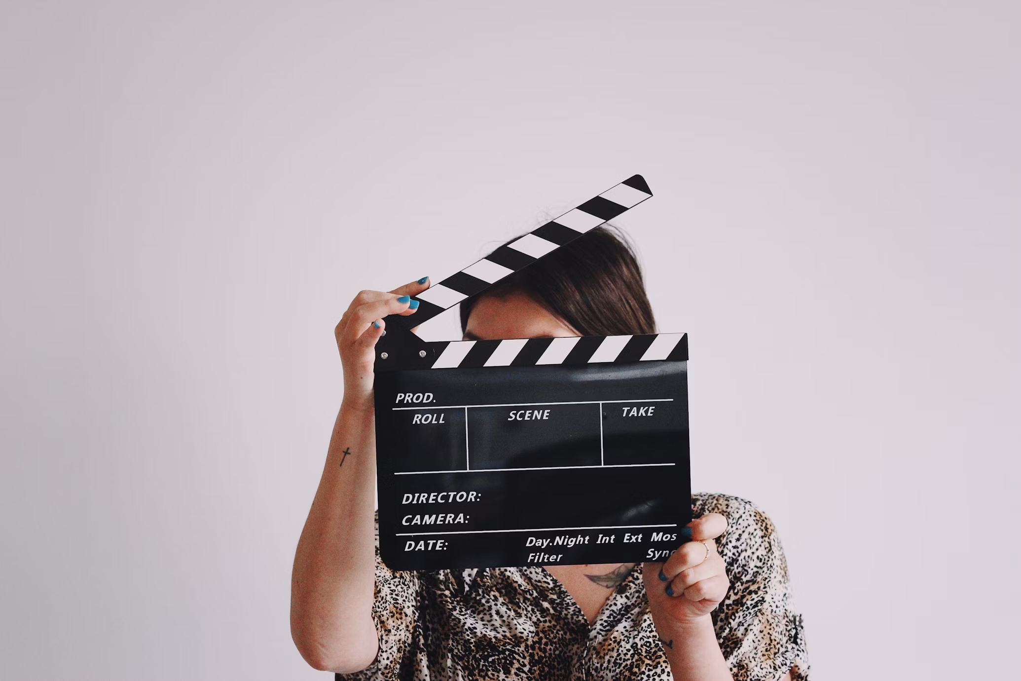 Mulher segurando claquete no rosto com alusão aos filmes