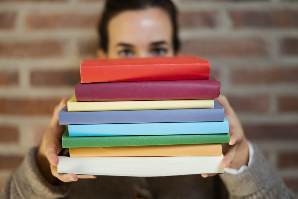 Mulher segurando livros coloridos